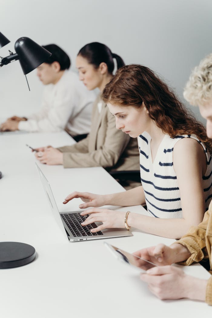 gallery-6 Diverse group of professionals working intently on laptops in a modern office.